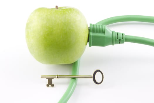 Golden key sits on electric cable with its plug inserted into green apple to represent the challenging key to a clean energy future