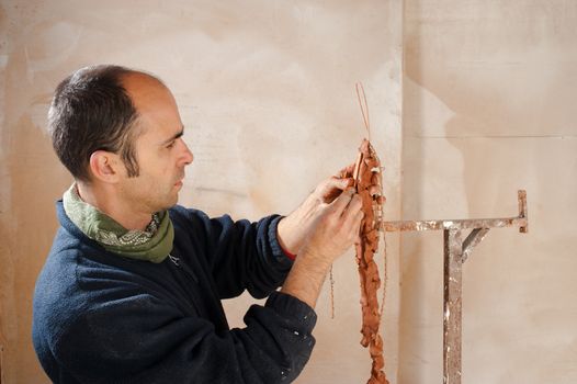 Artist in his studio working on a clay statue