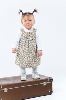 cute baby girl in nude stylish outfit and valise in studio