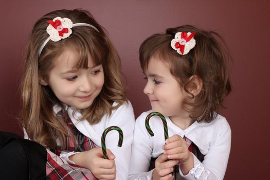 Two cute little sisters wearing Christmas dresses