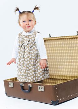 cute baby girl in nude stylish outfit and valise in studio