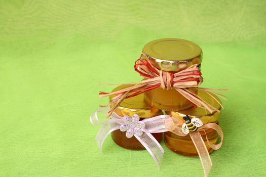 Three small honey jars with decorations on a green background