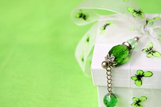 White gift box with green decorations and a crystal pin