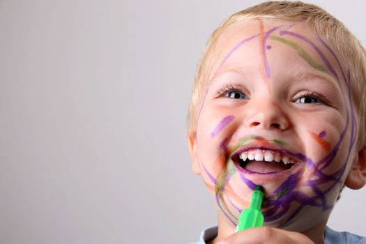 Laughing Toddler playing with colored pens making a mess