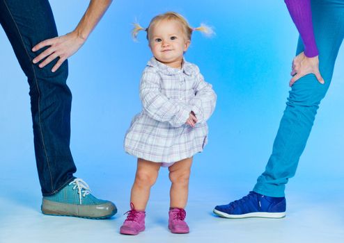 cute baby girl in pink and white stylish outfit with parents in studio