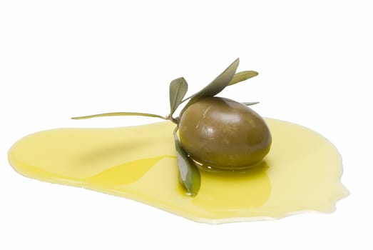 Green olive with leaves on some olive oil and isolated over a white background.