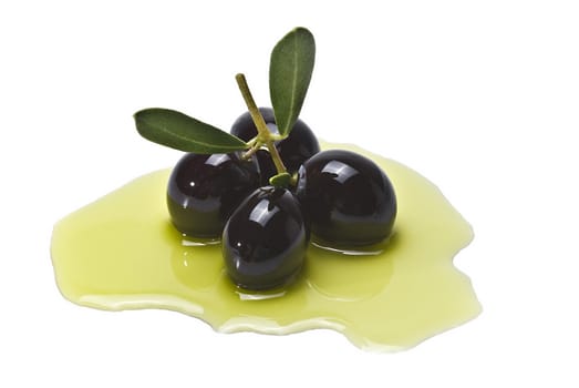 Premium black olives with leaves covered in olive oil and isolated over a white background.