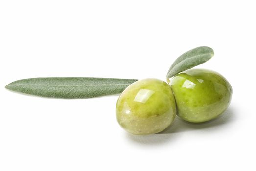 Two green olives with leaves isolated over white.