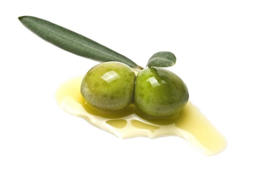 Green olives with leaves covered in olive oil and isolated over awhite background.