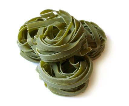 Curls of green unprepared pasta on white background