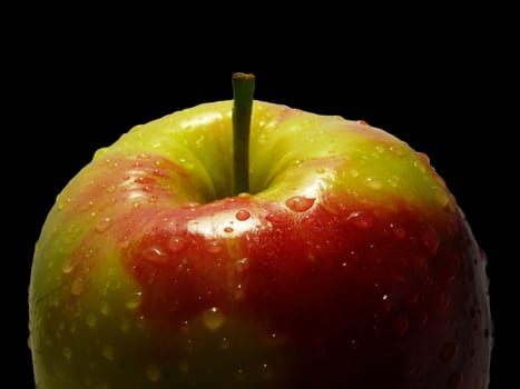 Fresh apple with drops of water on black background