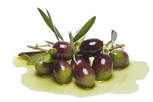 Green olives with leaves covered in olive oil and isolated over awhite background.