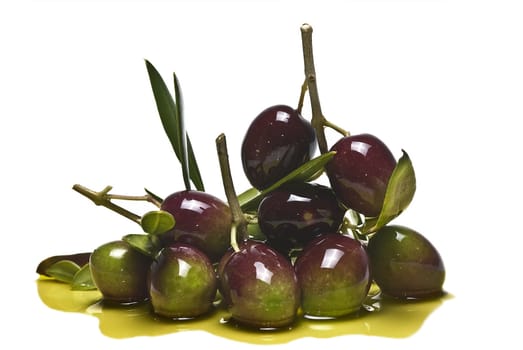 Green olives with leaves covered in olive oil and isolated over awhite background.