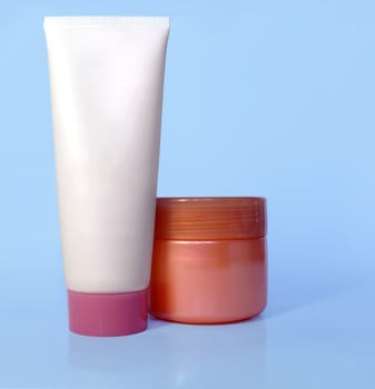 Cosmetic tube and pot of cream on light blue background, blank for applying new branding.