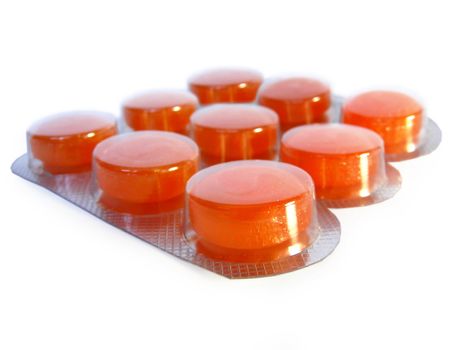 Bright orange pills in blister pack on white background