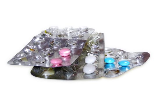 Pink, white and blue pills in blister pack on white background
