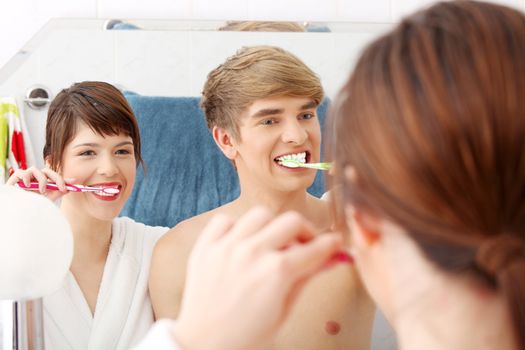 Young couple cleaning teeth together at bathroom.