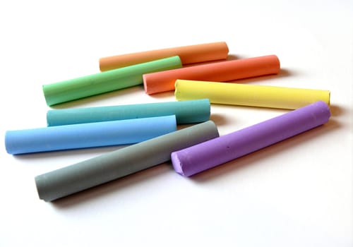 eight coloured pastels lying on white paper