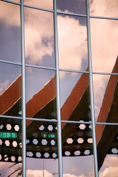 Modern office building with sky and clouds reflections 