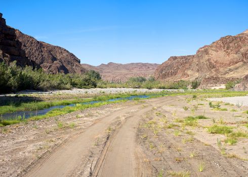 Kaokoland game reserve in Namibia, sand track going toward the Skeleton Coast Desert with a blue sky