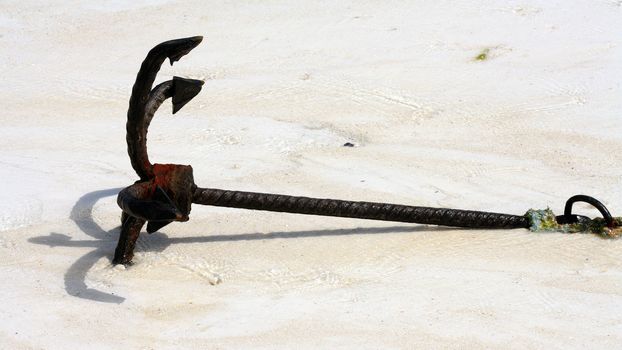 An old anchor on a white sand beach in Zanzibar