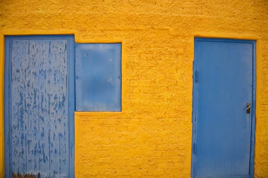 Close-up of a yellow house with blue windows and doors in Namibia