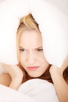 Young caucasian female on bed with pillow on her head. Insomnia concept