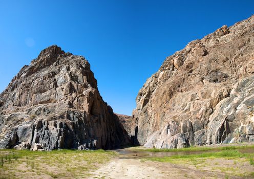 Kaokoland game reserve in Namibia, sand track going toward the Skeleton Coast Desert with a blue sky