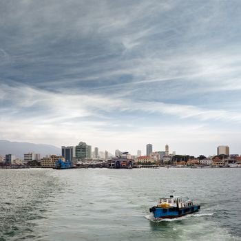 Penang cityscape with boats on ocean and skyscraper in Malaysia, Asia.