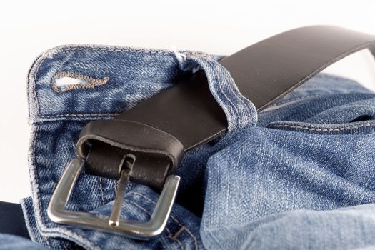 Blue jeans and a black leather belt over white background