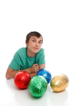 Inquisitive boy with four large foil wrapped chocolate easter eggs.  White background.  Space for copy.