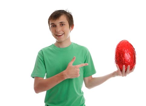 Happy smiling boy pointing to a large chocolate easter egg.  White background.