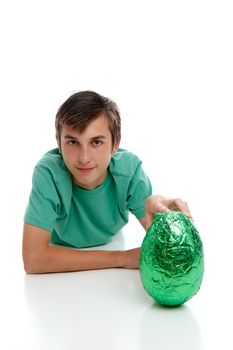 A boy holding a large green foil wrapped chocolate easter egg.  White background.