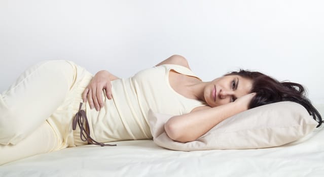 Pretty young brunette woman lying in bed