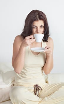 Young woman in bed holding a cup of coffee after she waken up