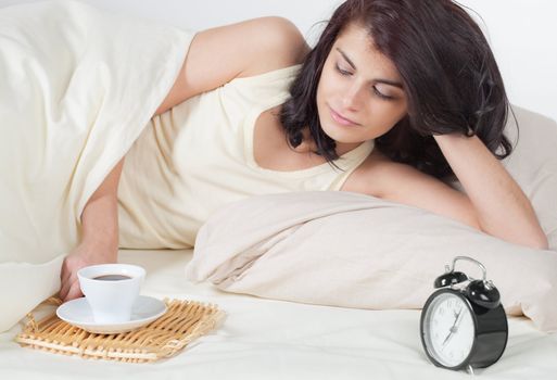Young woman in bed holding a cup of coffee after she waken up
