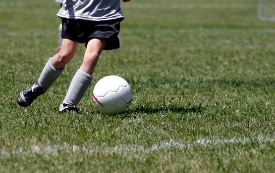 A young soccer player dribbling the ball.