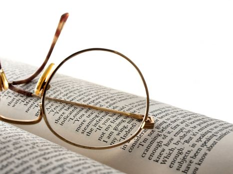 one lens of a pair of glasses sitting on an open book