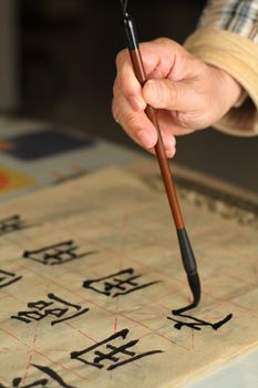 An old man is practicing callingraphy using a brush pen in his leisure time