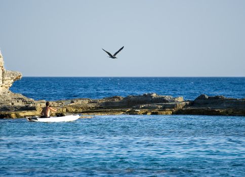 A man kayaking near the rocky beach