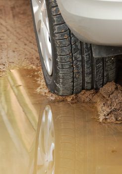 After rain - car wheel reflection in puddle on dirt road