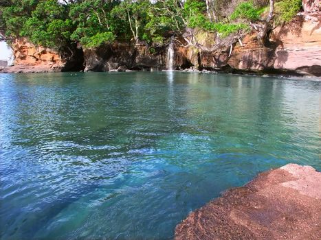 Waterfall flows into the ocean at Goat Island Marine Reserve on the North Island of New Zealand.