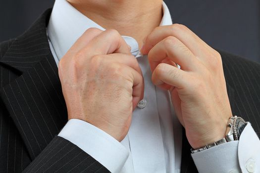 young man adjusting his suit on a black background 