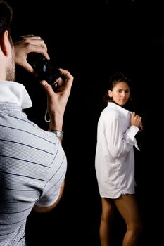 Guy taking photographs of his girlfriend in a studio environment