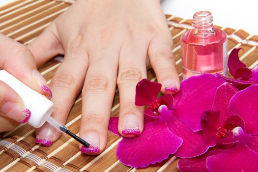 Beautiful hands with pink manicure holding purple orchid 