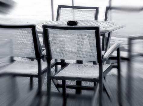 Four chairs and a table  in outdoor restaurant near the sea - A zoom effect black and white photo 