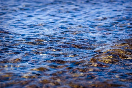 Blue wavy water and rocky coast close up photo