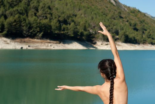 Young woman at early morning yoga on the shores of  a lake