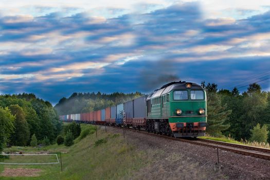 Freight train hauled by the diesel locomotive passing the forest
