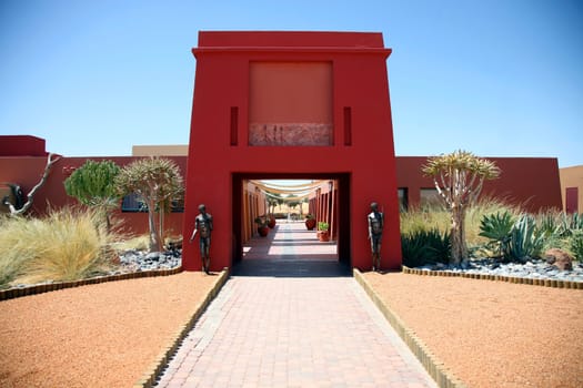 Entrance of a red building in Sossusvlei Nambia with 2 statues 